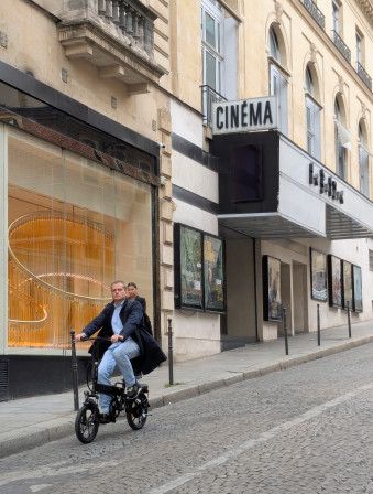 Un type à velo descend la rue, le cinéma Le Balzac en arrière plan.