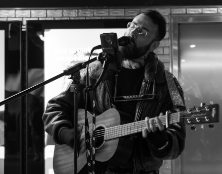 Un musicien dans le métro qui s'accompagne à la guitare, version N&B