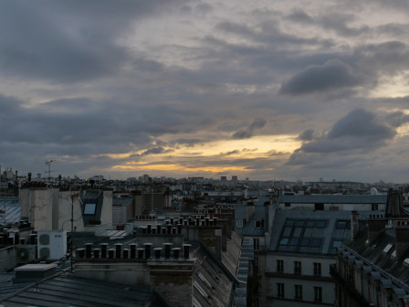 50 nuances de gris dans le ciel et sur les immeubles. Dans une trouée de nuages on devine la lumière dorée du soleil levant.