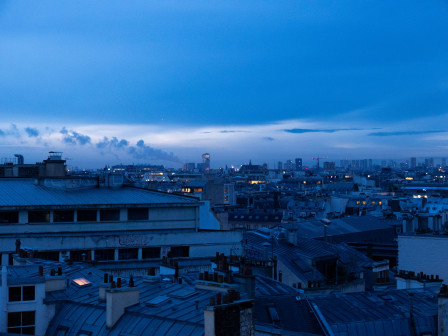 Les lumières de Paris comme points orangés chaleureux dans la lumière bleue de fin de nuit.