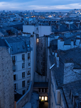 Les lumières de Paris comme points orangés chaleureux dans la lumière bleue de fin de nuit.