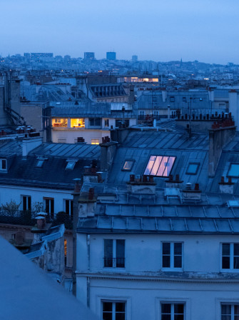 Les lumières de Paris comme points orangés chaleureux dans la lumière bleue de fin de nuit.